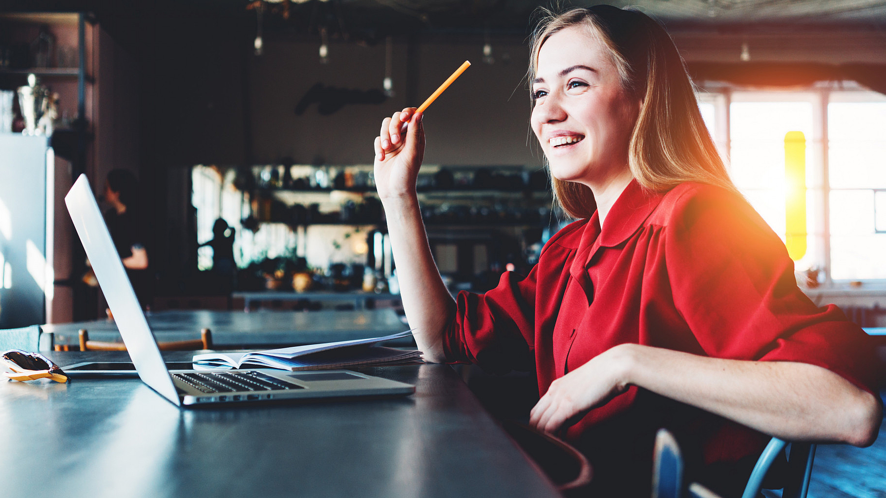 Frau mit Stift in der Hand vor einem Laptop